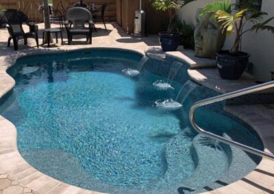 Smaller wavy edged inground pool with stairs and different depths with sitting areas