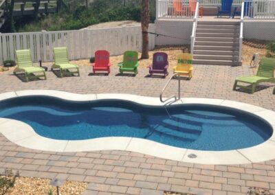 Smaller wavy edged inground fiberglass pool with stairs, sitting areas and different depths