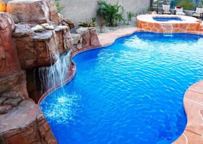 Large curved edge inground pool with large waterfall and attached spa