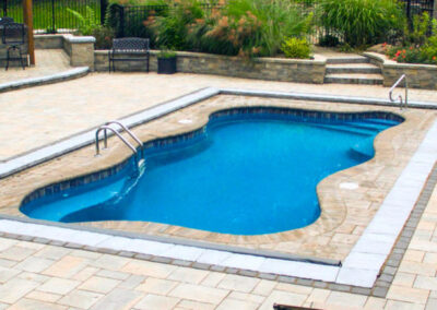 Wavy edged inground pool with stairs and sitting area