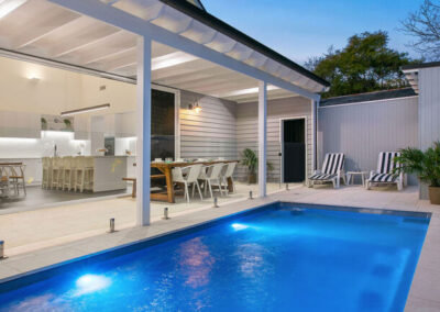 Rectangular inground fiberglass pool at night with underwater lights