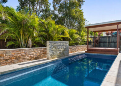 Rectangular pool with stone waterfall and pergola at one end