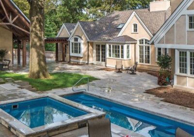 Rectangular inground pool with square attached hot tub in backyard