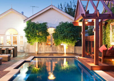 Backyard inground pool at night with lights