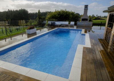 Rectangular inground fiberglass pool in background with wood decking