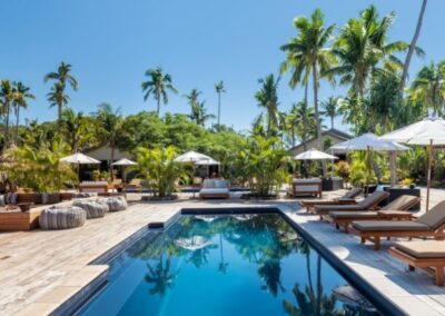 Rectangle inground fiberglass pool with loungers and palm trees