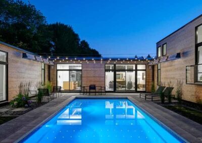 Rectangular inground fiberglass pool at night in backyard