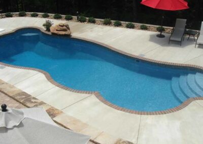 Fiberglass inground pool in the shape of a kidney and curves along the edges