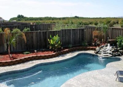 Oval inground fiberglass pool with wavy edges and stairs in one corner
