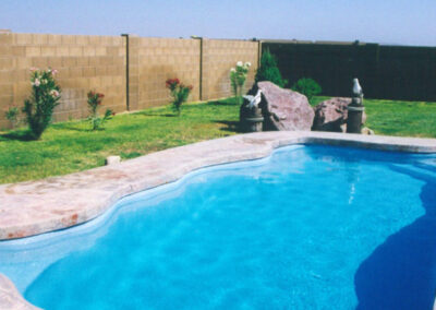 Oval inground pool with wavy edges and stairs in one corner