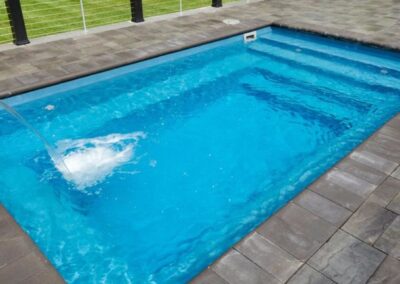 Inground fiberglass pool with sitting around all around and steps on one end
