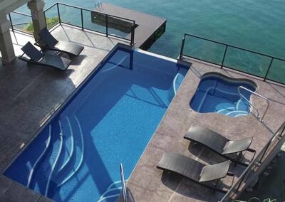 Rectangular inground pool with 2 sets of steps in corners and sitting area in other 2 corners